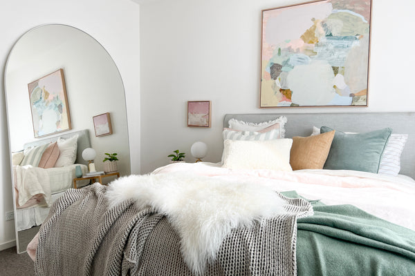 Arched leaner mirror in a norsu-styled bedroom, reflecting the bed and artwork