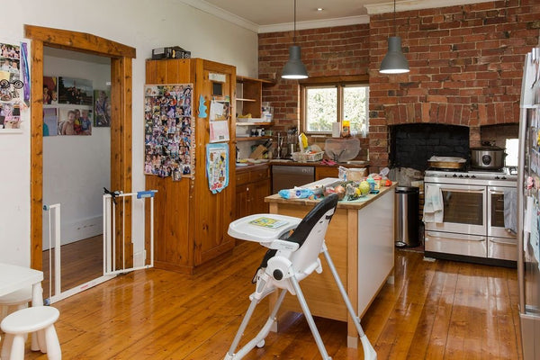 Cozy family kitchen with wooden floors, brick walls, and child safety gate as part of Project Seven home renovation.