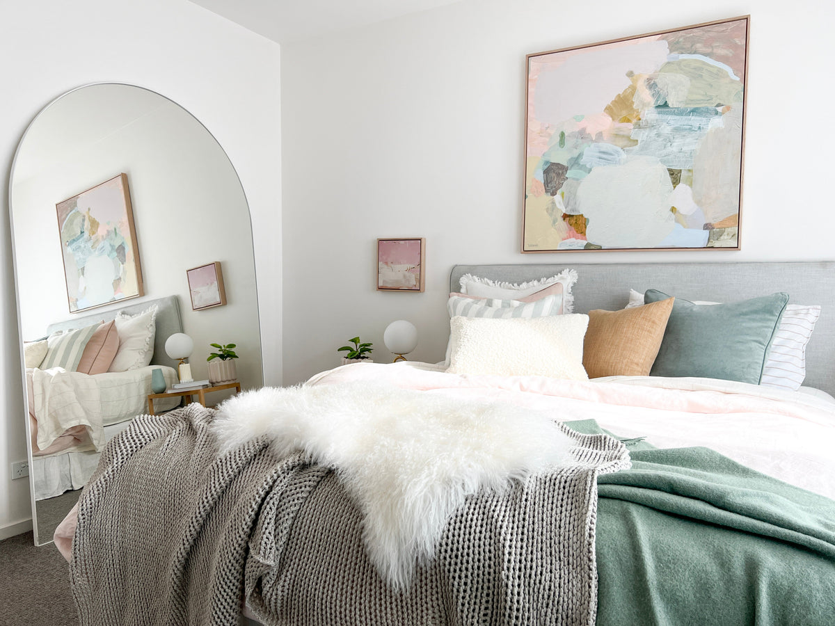 Arched leaner mirror in a norsu-styled bedroom, reflecting the bed and artwork