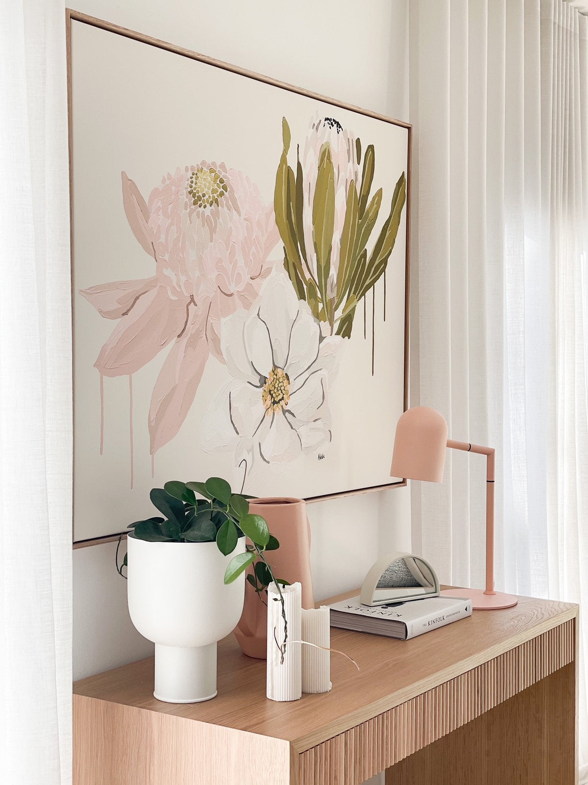 Adele Naidoo Native '21 collection botanical floral canvas print in soft pastels above wooden console with modern pink lamp and white vase with greenery