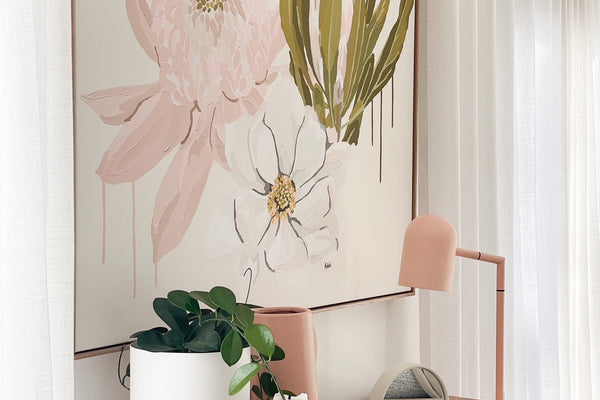 Adele Naidoo Native '21 collection botanical floral canvas print in soft pastels above wooden console with modern pink lamp and white vase with greenery