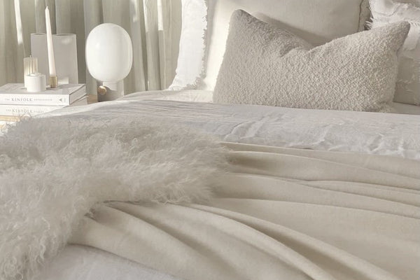 Cozy winter white tonal bedroom with layered textures and soft linens for calming monochromatic room creation.