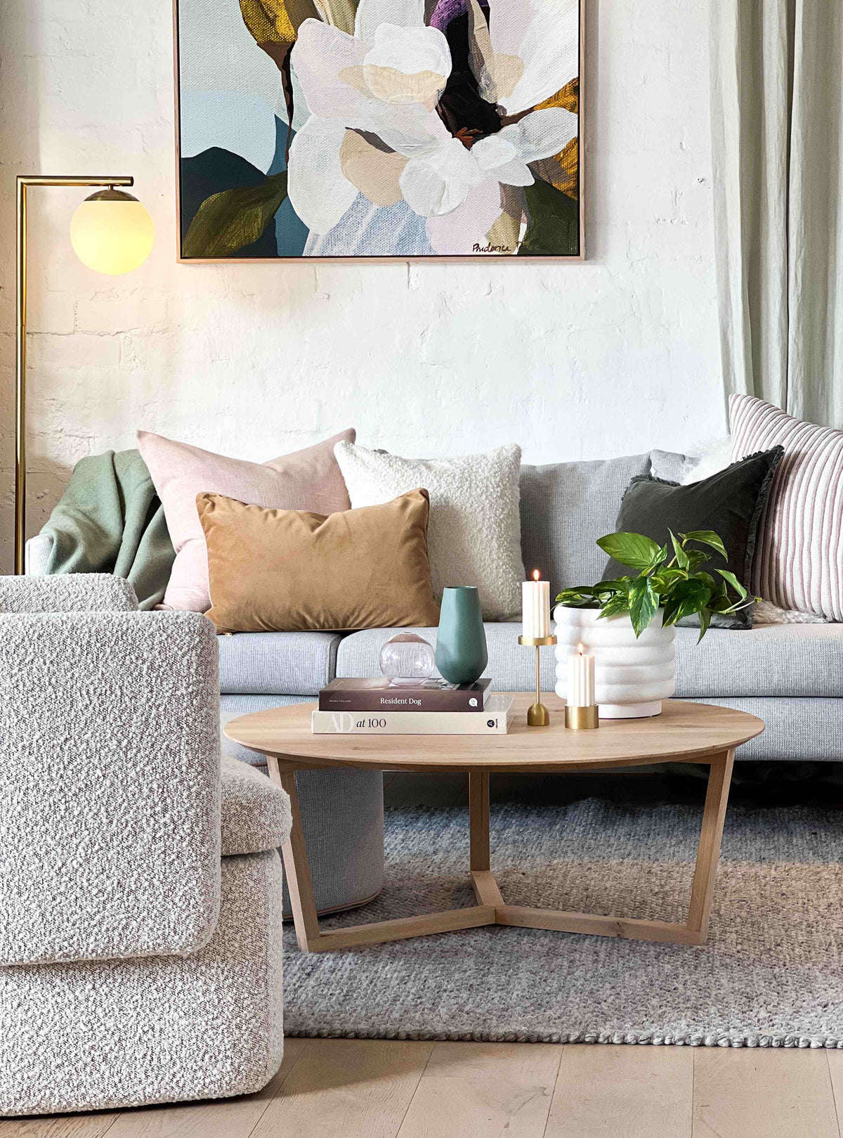 Cozy modern living room with soft textured sofa, warm cushions, wooden coffee table, indoor plants, and abstract wall art.