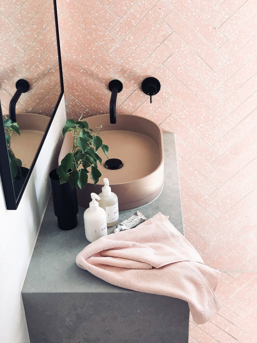 Minimalist blush terrazzo powder room with sleek black wall-mounted tapware and concrete sink by norsuHOME styleLAB