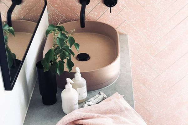 Minimalist blush terrazzo powder room with sleek black wall-mounted tapware and concrete sink by norsuHOME styleLAB