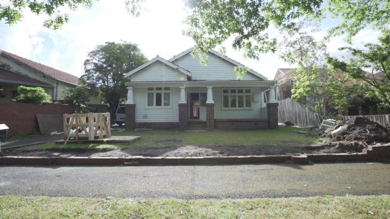 Front view of a suburban house with a yard under renovation for norsuHOME - The Beginning