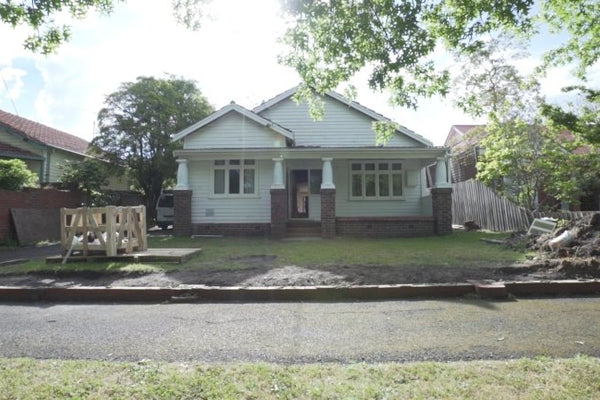 Front view of a suburban house with a yard under renovation for norsuHOME - The Beginning
