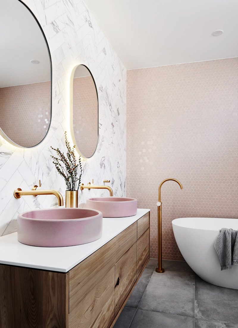 Modern bathroom with pink vessel sinks, gold fixtures, round mirrors, freestanding tub, and wood vanity in norsuHOME reveal