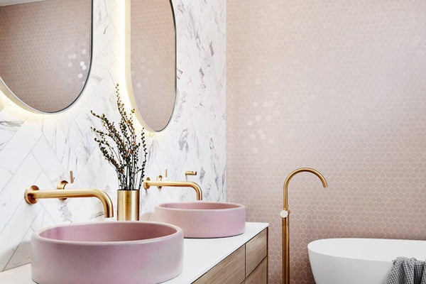 Modern bathroom with pink vessel sinks, gold fixtures, round mirrors, freestanding tub, and wood vanity in norsuHOME reveal