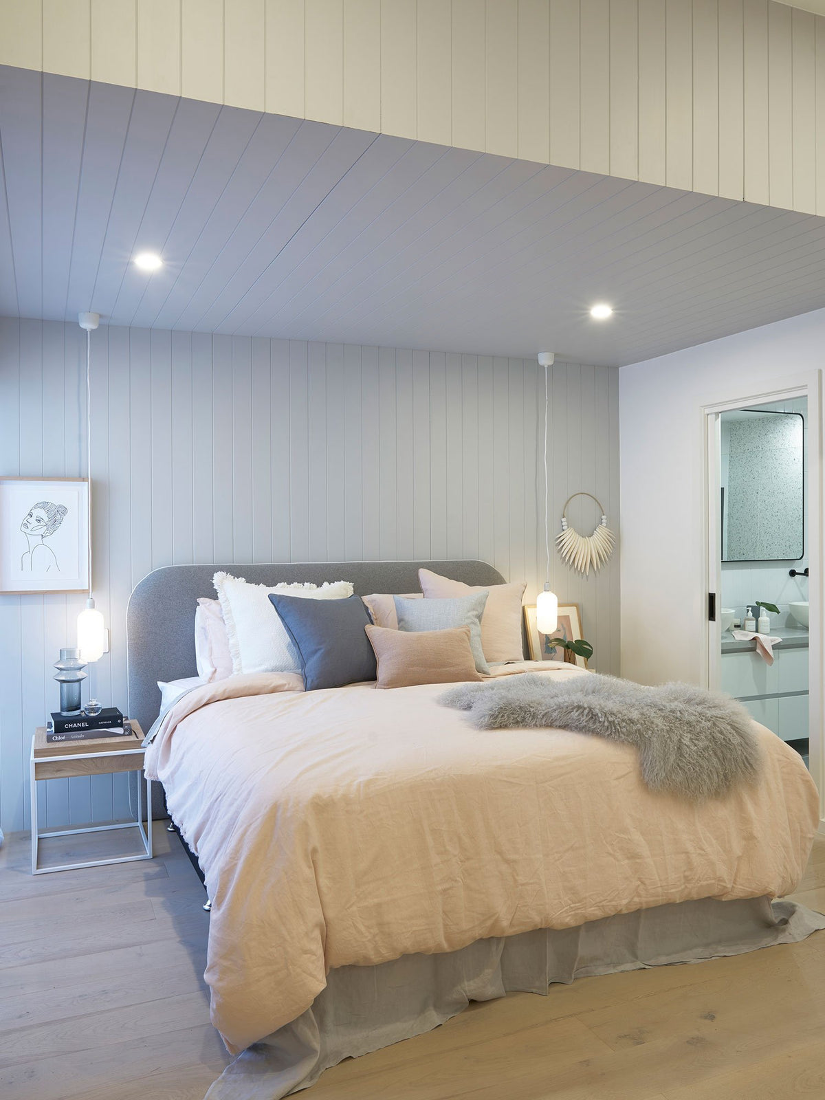 Cozy adults only retreat bedroom with soft pastel linens, textured accents, and modern ensuite visible through open door