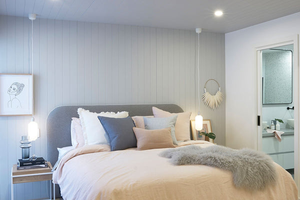 Cozy adults only retreat bedroom with soft pastel linens, textured accents, and modern ensuite visible through open door