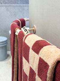 Loop Home Hand Towels in ruby and almond blush pinstripe hanging on a bathroom rail
