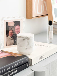 Stackable marble jewellery organiser canister on white shelf with books and framed photo nearby