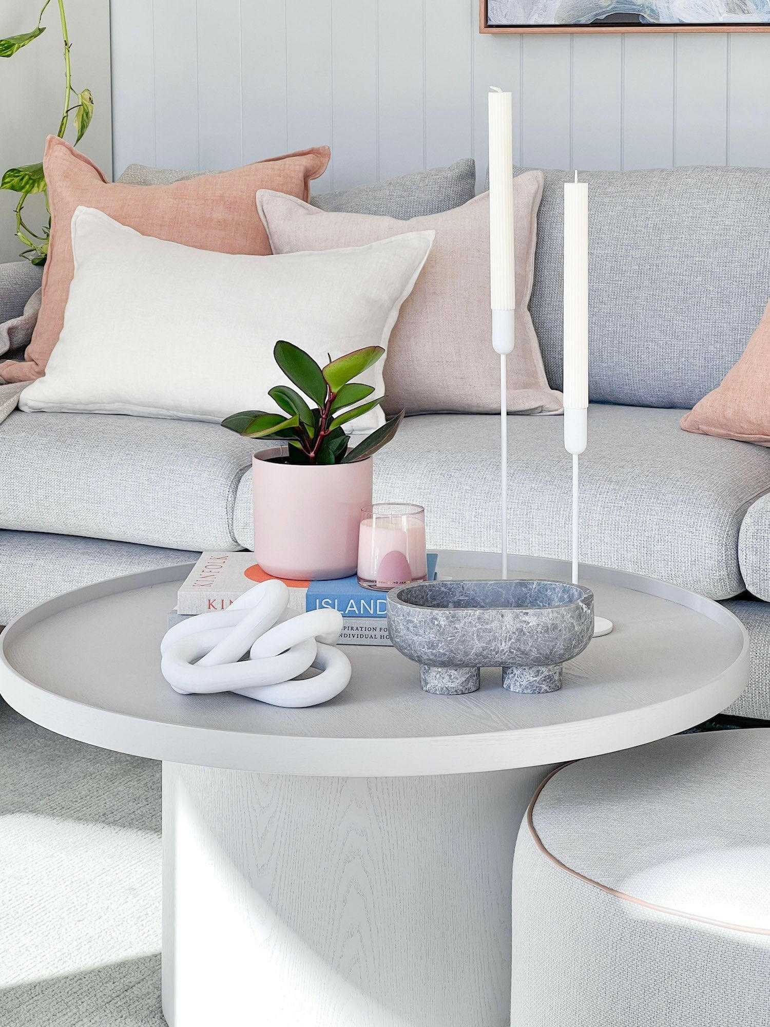 CoTheory Marble Footed Oval Tray in Tundra Grey Marble on a white round table with candles and decorative items in a modern living room setting
