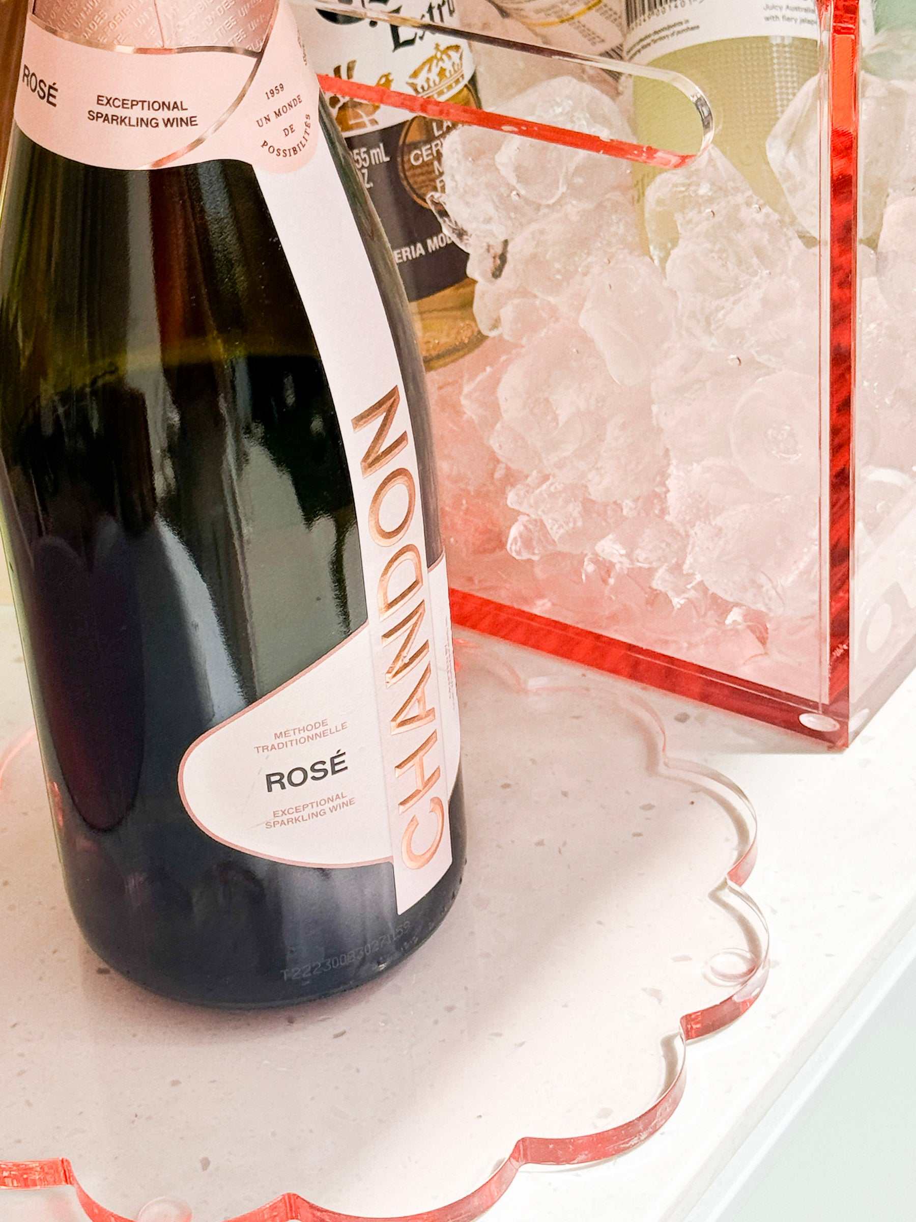 norsu Studio Perspex scallop trivet tray in translucent ochre with blush-pink tone on white surface holding a bottle and ice bucket