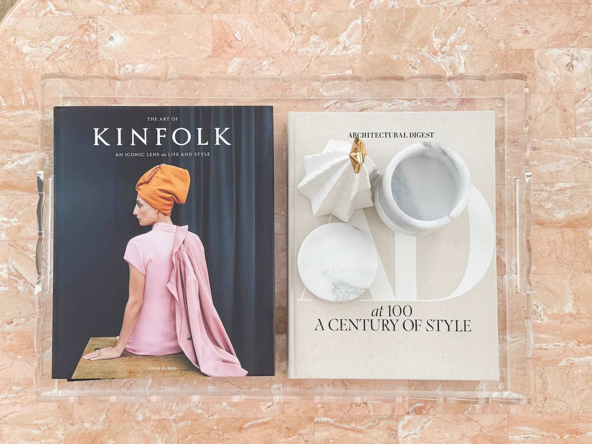 norsu Studio clear scalloped perspex tray with books and decor on marble surface