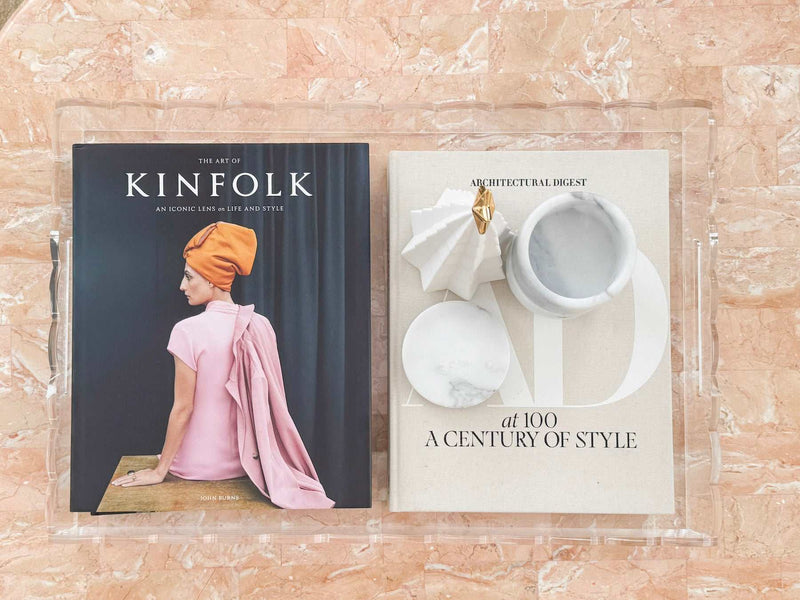 norsu Studio clear scalloped perspex tray with books and decor on marble surface