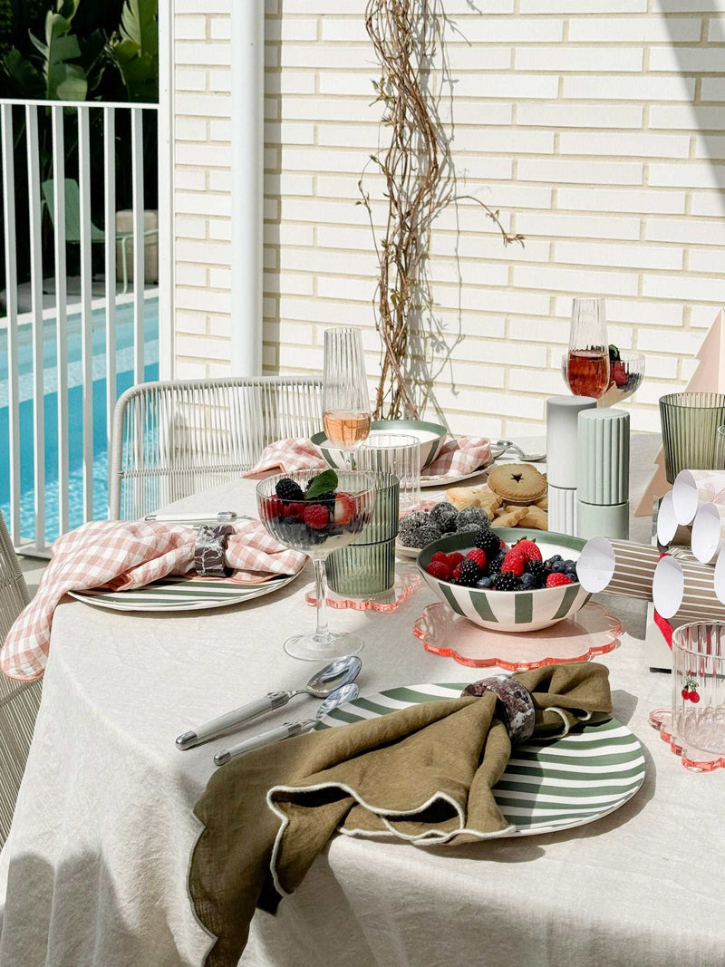 Set of four green Saltara RPET tumblers with ribbed texture on an outdoor dining table with plates and berries.