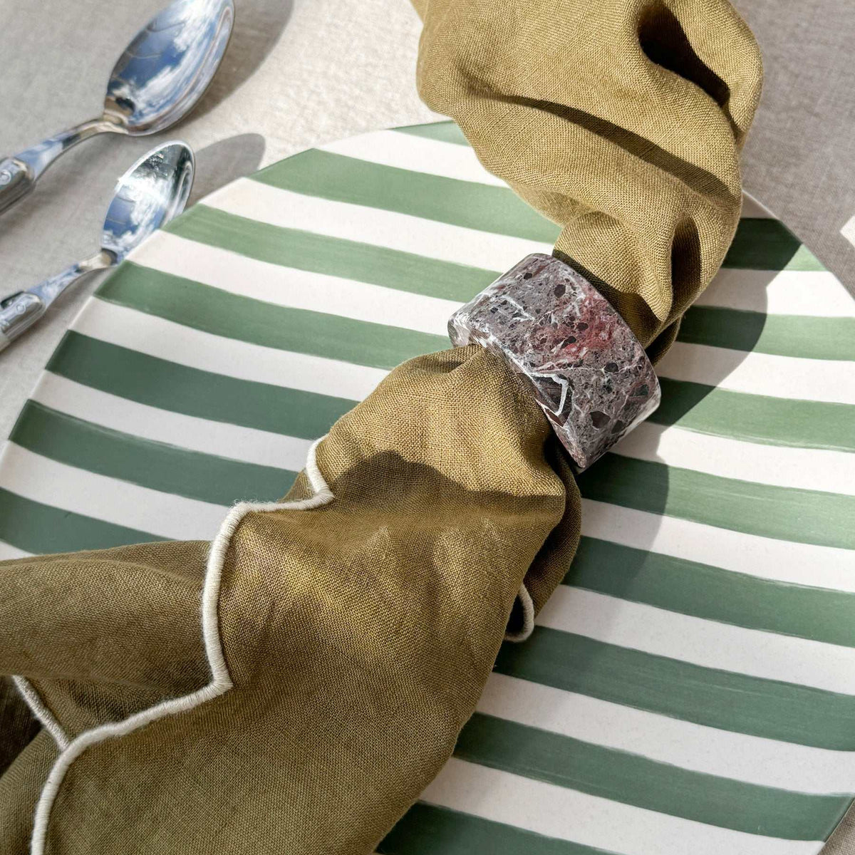 Green and white striped Davis & Waddell Saltara Bamboo Fibre Dinner Plate with olive cloth napkin and silver spoon set