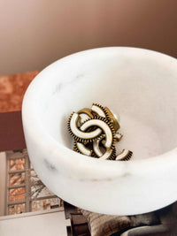 Stackable marble jewellery organiser with unique veining and compact cylindrical design holding gold earrings