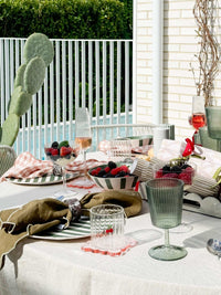 Davis & Waddell Saltara Bamboo Fibre Dinner Plates set with green and mint stripes on outdoor picnic table with glassware and fruit