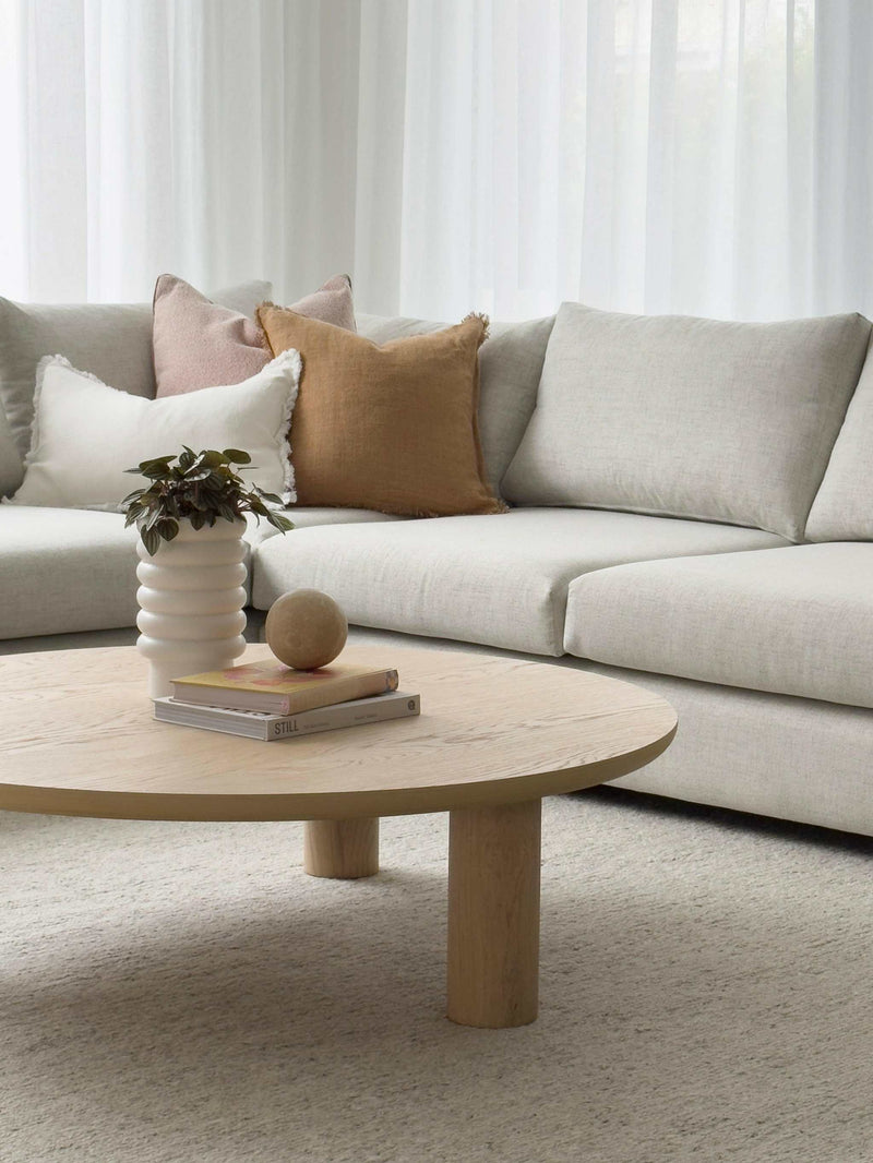Modern norsuHOME sofa with neutral cushions and a wooden round coffee table in a bright living room