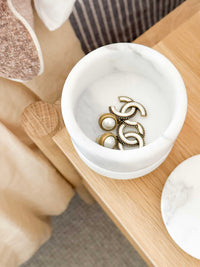 stackable marble jewellery organiser with unique veining holding earrings on wooden surface