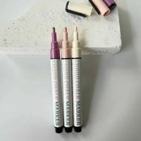Set of three neutral color liquid chalk markers with fine reversible nibs on a concrete block background