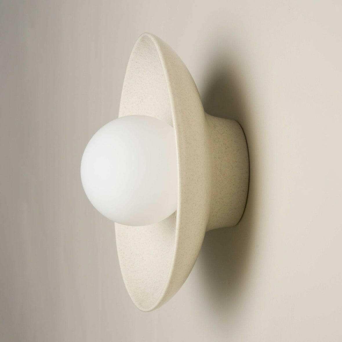 Robert Gordon ceramic dish wall sconce with round white LED globe in poppyseed finish mounted on wall