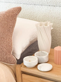 Stackable marble jewellery organiser with removable layers on wooden bedside table