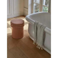 GlobeWest Hanson Round Stool in cherry ceramic glaze beside bathtub on wooden floor