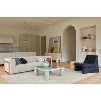 Spacious living room featuring a GlobeWest Bower Frame Rug in rose beneath a modern sofa and chair setup