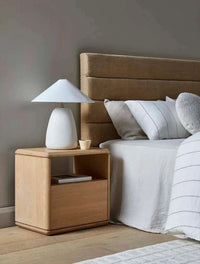 GlobeWest Lorne Pebble Table Lamp with white sand ceramic base and cotton linen shade on wooden bedside table in modern bedroom