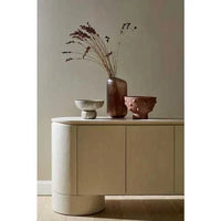 Minimalist GlobeWest Pluto Buffet in porcelain with rounded edges and circular legs, styled with decorative vases on top