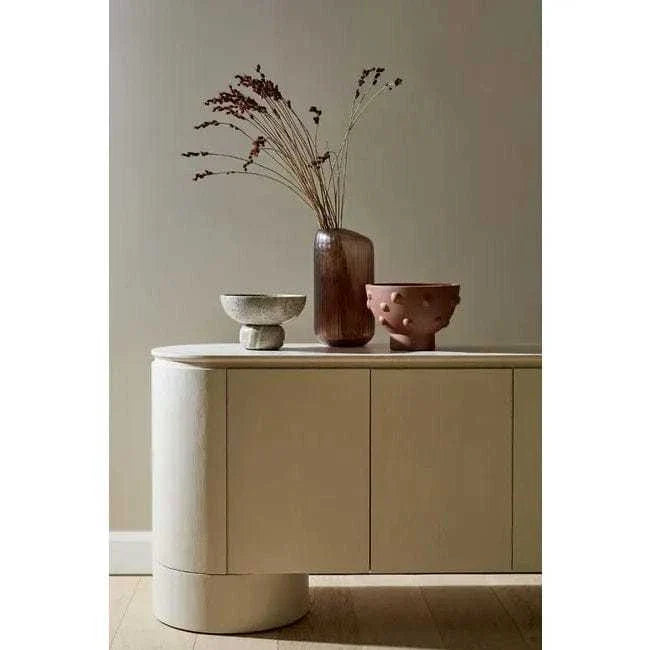Minimalist GlobeWest Pluto Buffet in porcelain with rounded edges and circular legs, styled with decorative vases on top
