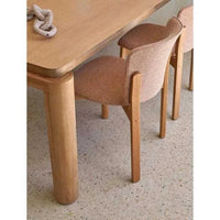 GlobeWest Sketch Pinta Dining Chair with pecan leather upholstery and light oak frame next to wooden dining table