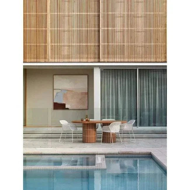 GlobeWest Seville Tile Oval Dining Table in pearl white with tiled oval base, set outdoors by pool with white chairs and modern decor