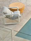 GlobeWest Seville Tile round honey coffee table with white grid pattern by poolside