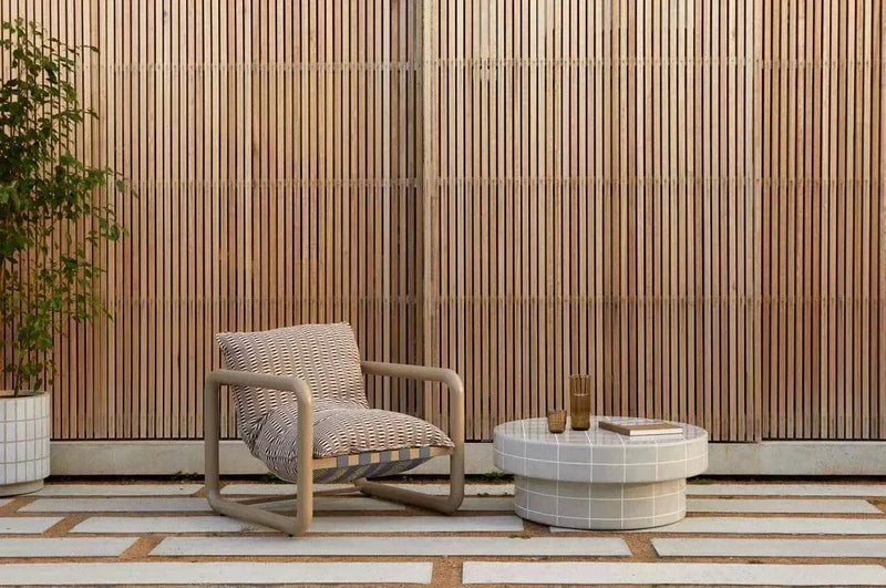 GlobeWest Seville Tile round honey coffee table with tiled surface and modern outdoor chair on patio