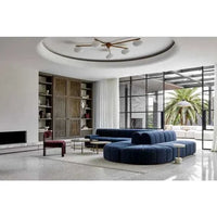 Modern living room featuring a GlobeWest Bower Frame Rug in cloud color under a navy blue sectional sofa with large windows and elegant ceiling light