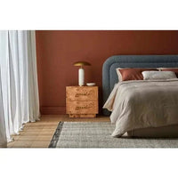 Trove Burl Bedside Table in light burl veneer with brass handles next to bed in modern bedroom setting