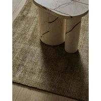 GlobeWest Tepih Neptune Rug in olive hand-woven wool blend with subtle rustic texture under marble table