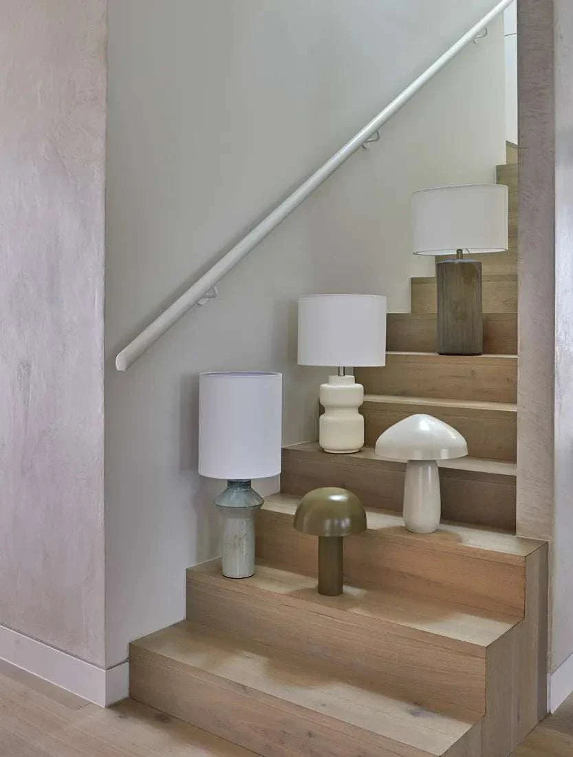 Easton Curve Table Lamp in gloss oyster grey iron shade and base on wooden stairs with soft warm lighting