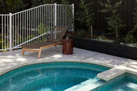 Petra Sphere Side Table in burgundy glaze beside a pool with a lounge chair on a patio
