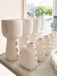 White architecturally shaped Eva Vases in varying sizes displayed indoors near a window