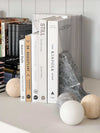 Orbit Sphere Table Sculpture in beige travertine stone displayed as a decorative sphere beside books.
