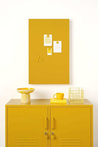 Mustard Made lockers magnetic storyboard with powder coated finish in mustard yellow above matching mustard yellow lockers with decor.