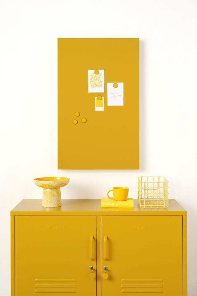 Mustard Made lockers magnetic storyboard with powder coated finish in mustard yellow above matching mustard yellow lockers with decor.