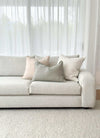 Minimalist light beige norsuHOME sofa with soft textured cushions in neutral tones against sheer white curtains.