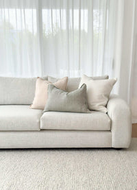 Minimalist light beige norsuHOME sofa with soft textured cushions in neutral tones against sheer white curtains.